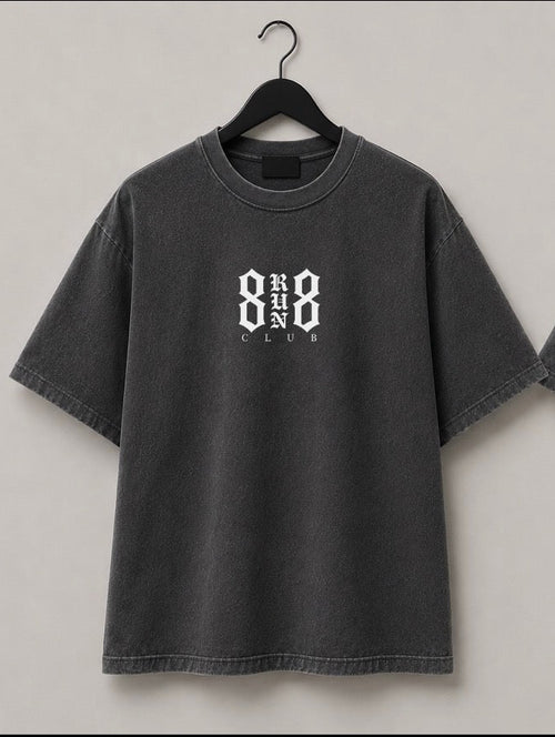 Two views of a dark gray washed t-shirt hanging on black hangers against a light gray wall. The front view shows a small white '888 CLUB' logo on the left chest, and the back view shows a large white '888 RUN CLUB' graphic.