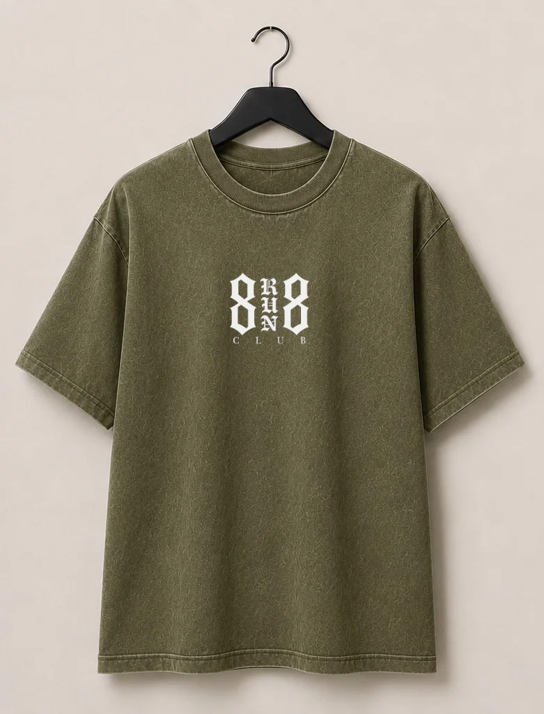 An olive green short-sleeve t-shirt shown from both front and back, hanging on black hangers against a light beige wall. The front features a small white graphic on the left chest, and the back features a large white graphic reading '8 RUN 8 CLUB'.